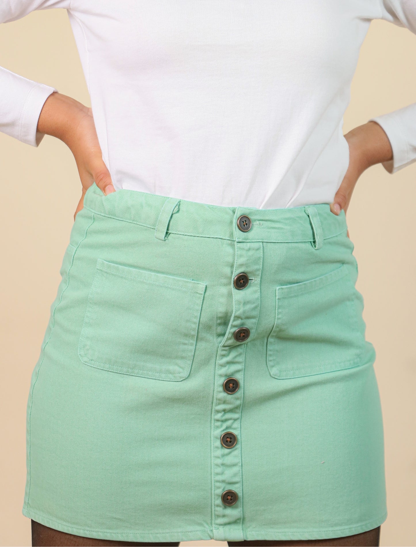 Light green skirt with buttons on a beige background