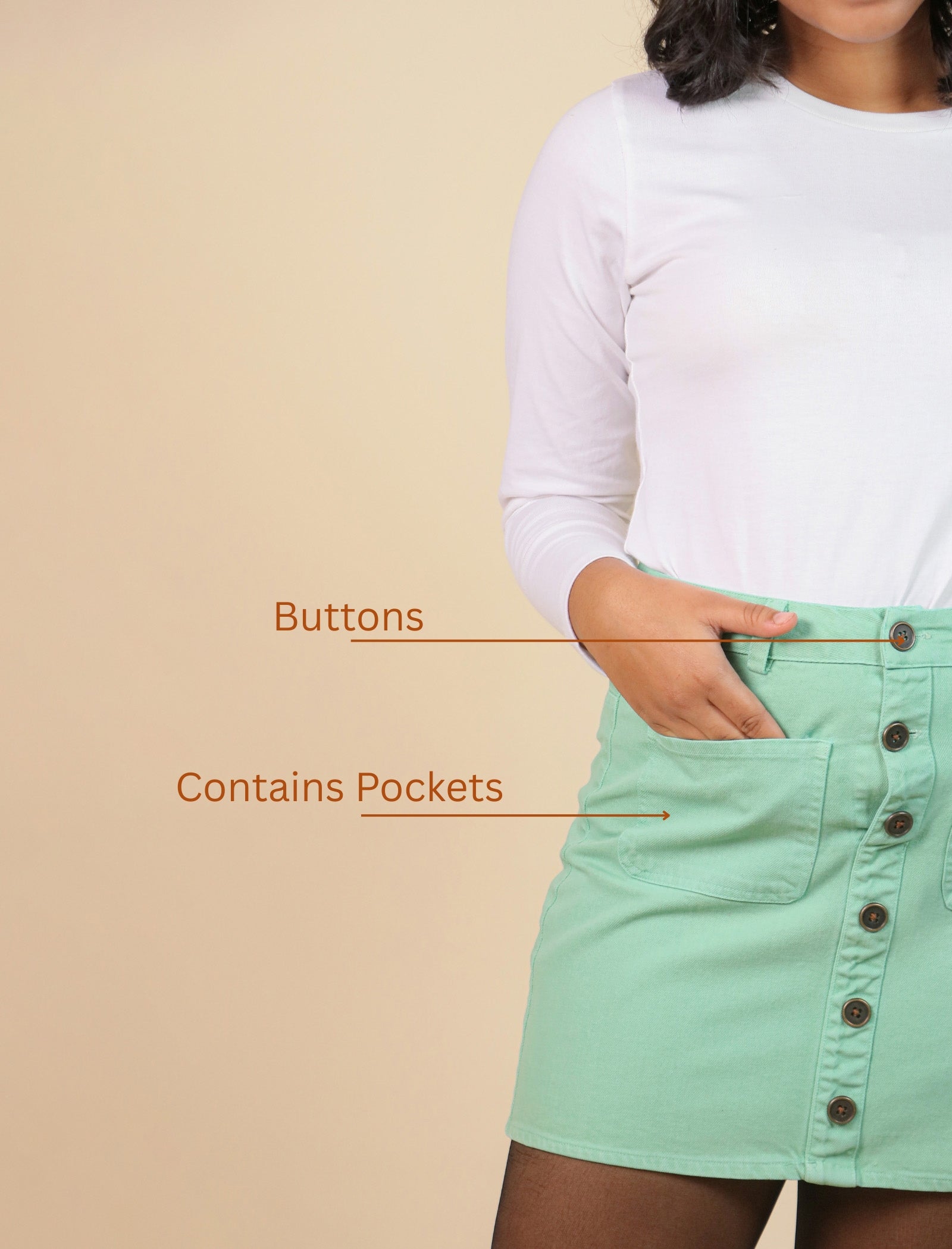Green skirt with button details and pockets on a beige background