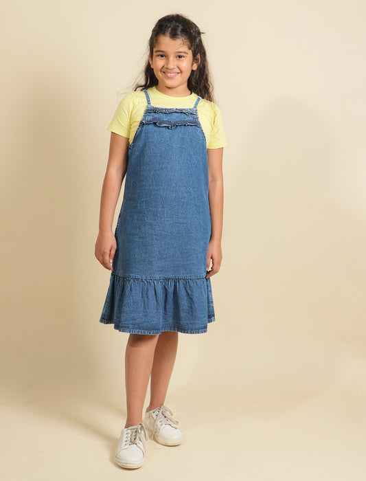 Girls wearing a denim dress over a yellow shirt on a beige background