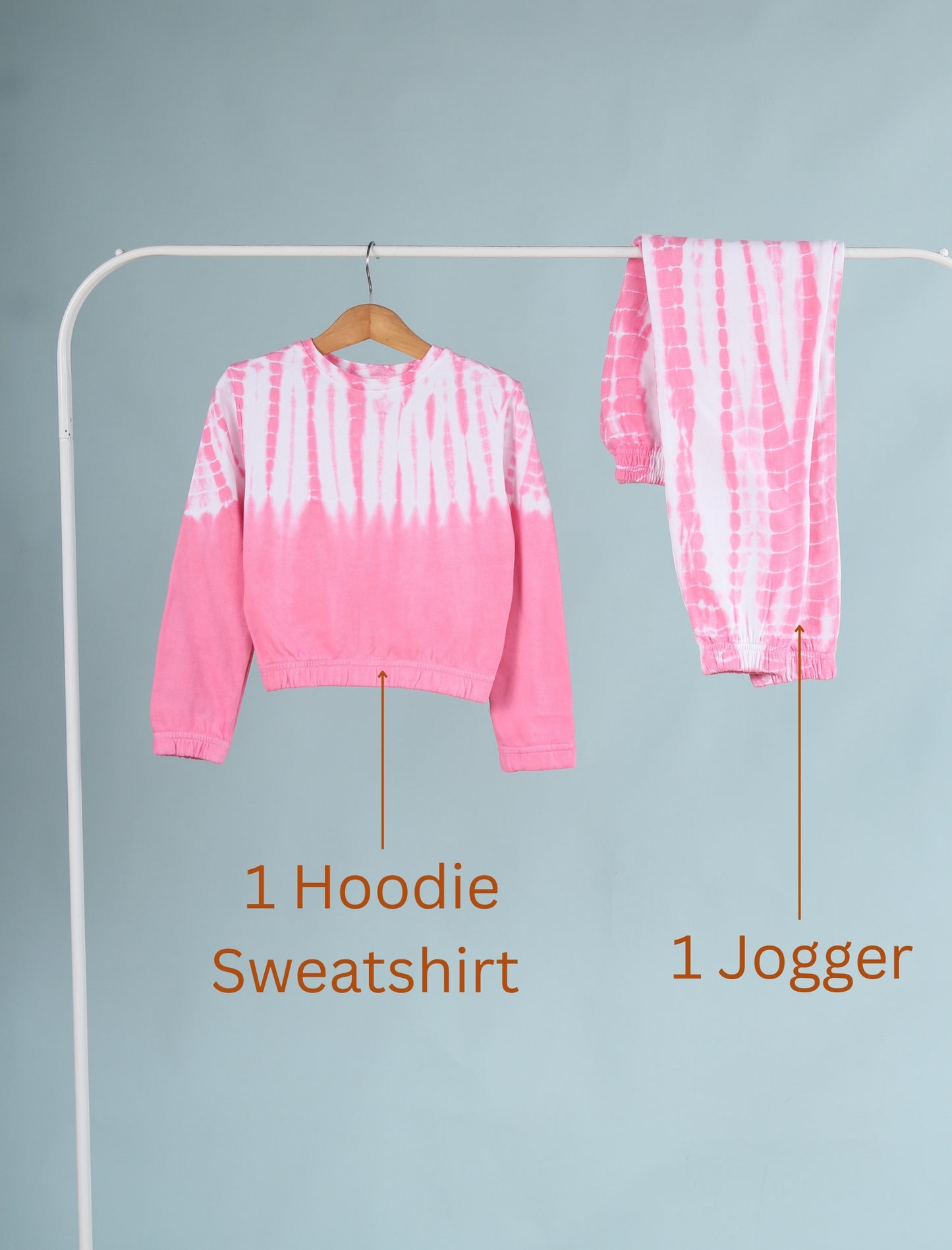 Pink tie-dye hoodie and jogger set on a rack against a gray background