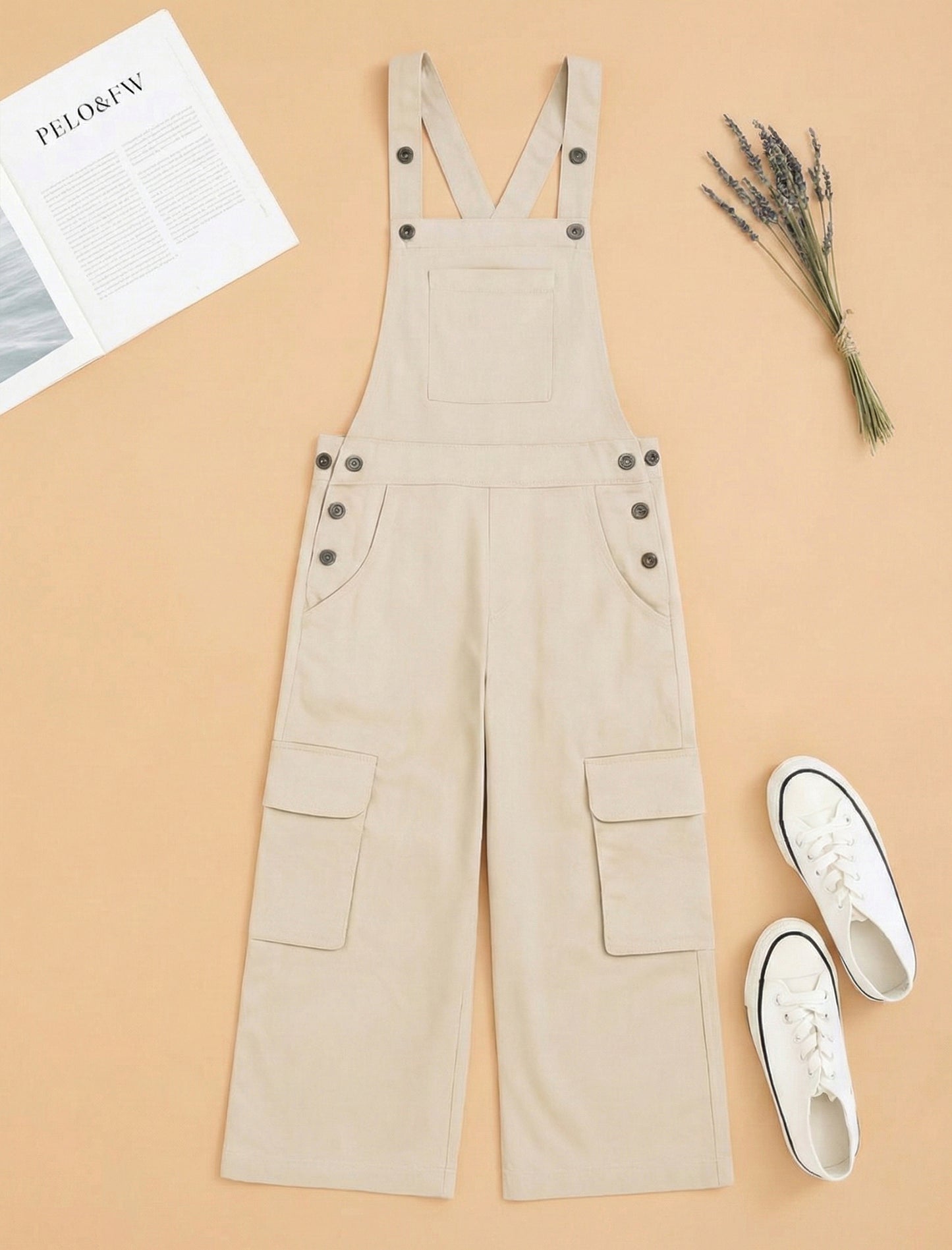 Beige overalls on a beige background with white sneakers and a newspaper.