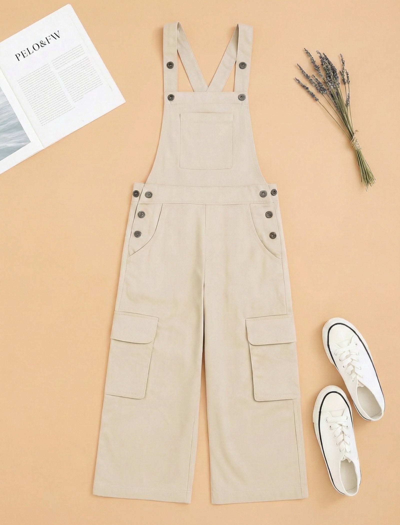 Beige overalls on a beige background with white sneakers and a newspaper.