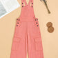 Peach denim overalls on a beige background with a magazine and decorative items.