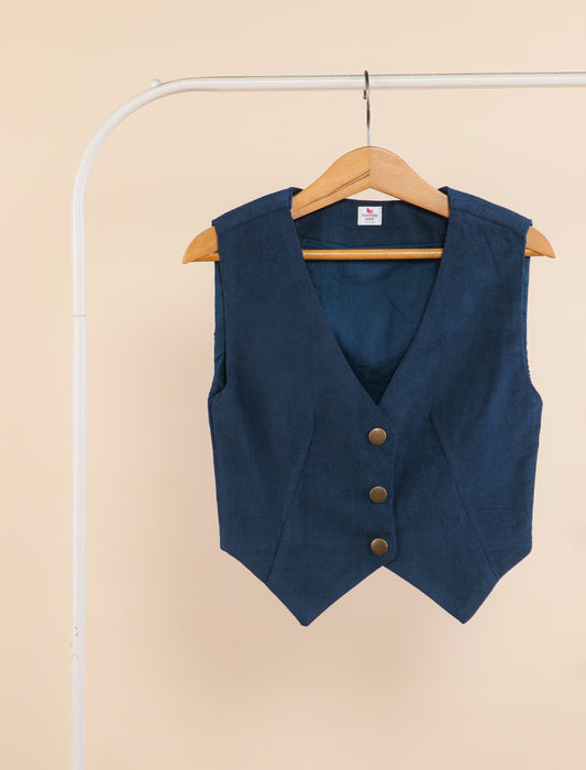 Blue vest with brown buttons on a hanger against a beige background