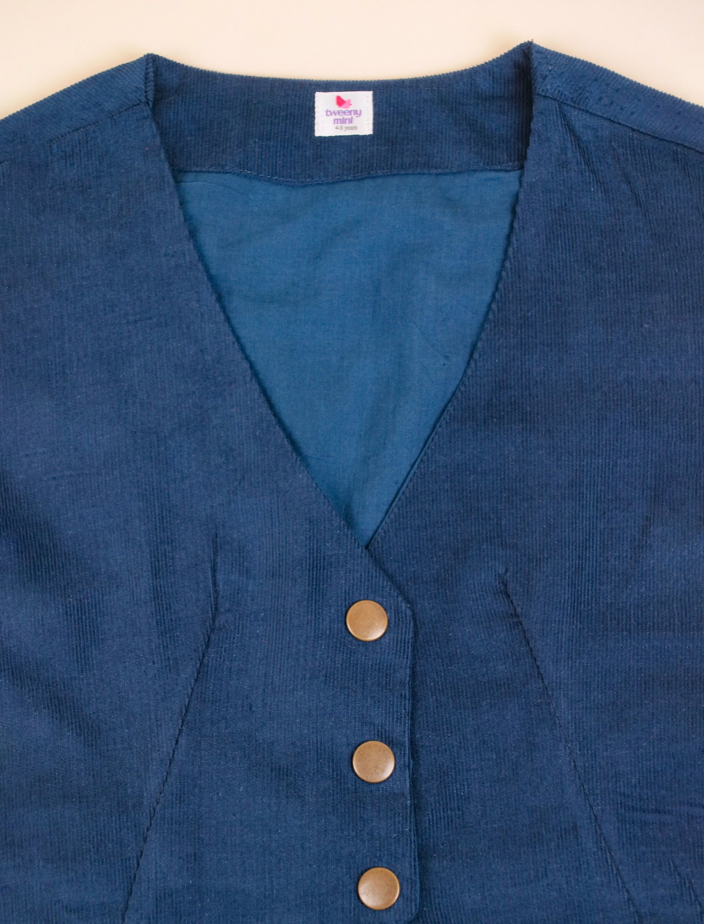 Blue vest with buttons on a beige background