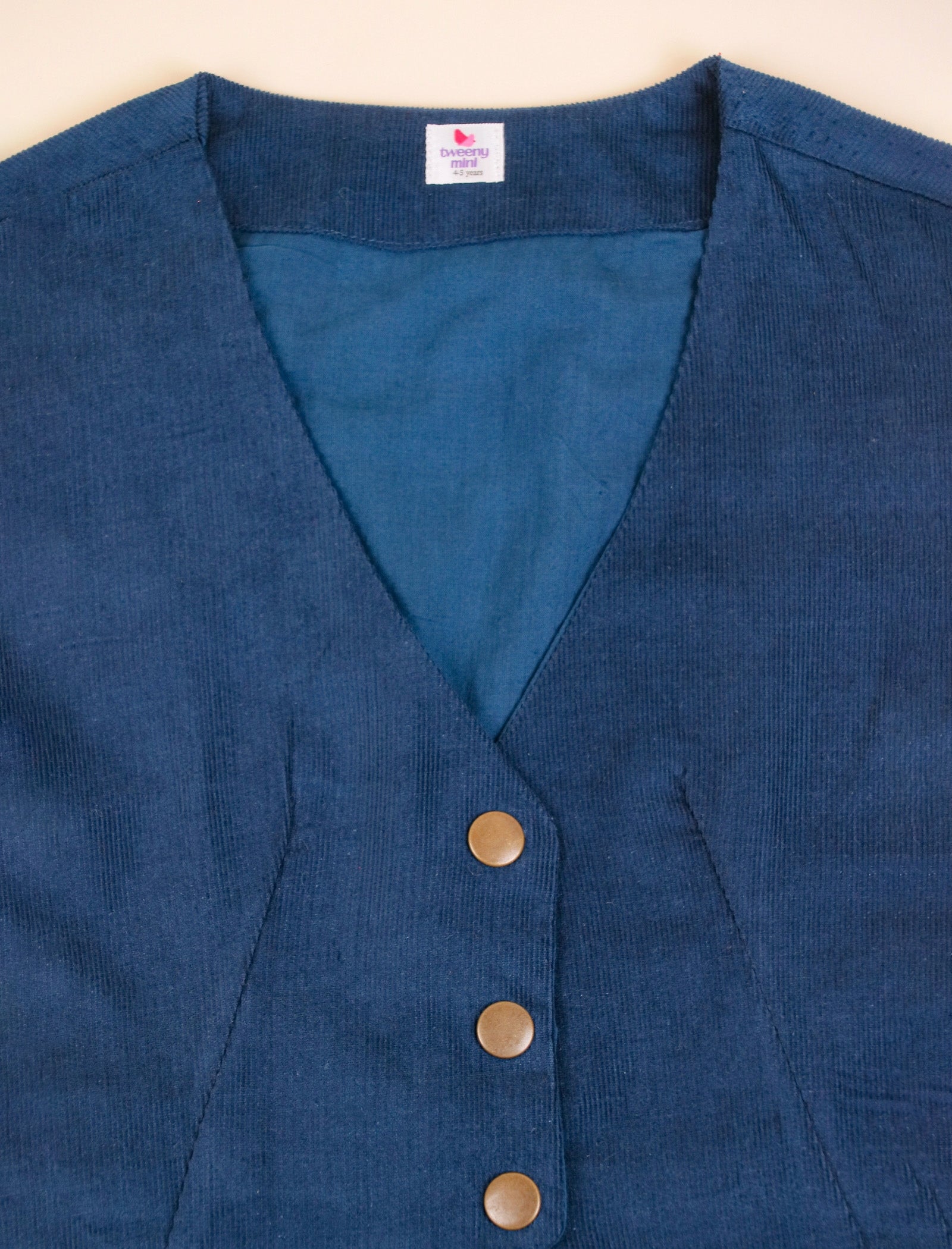 Blue vest with buttons on a beige background