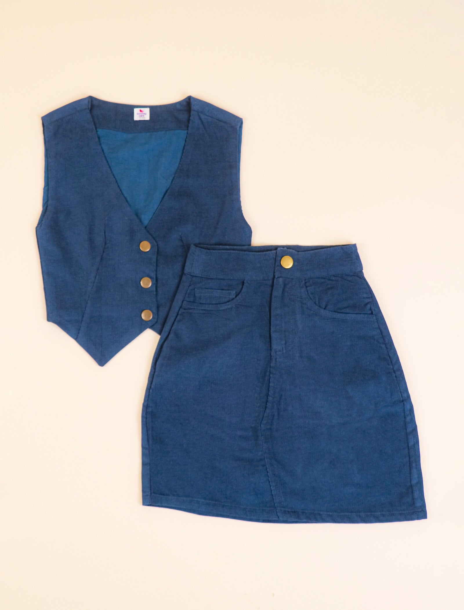 Blue corduroy vest and skirt set on a beige background