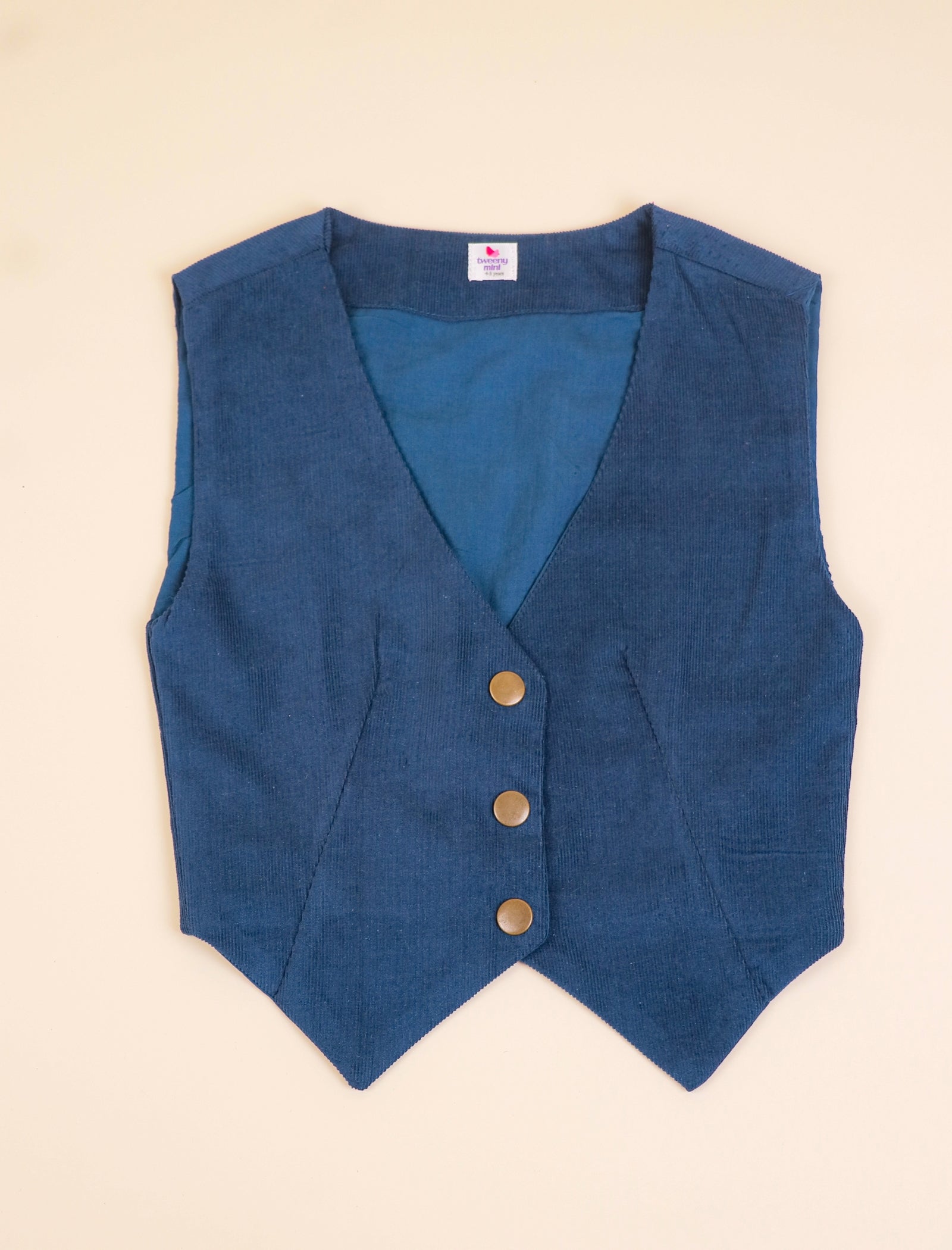 Blue vest with buttons on a beige background