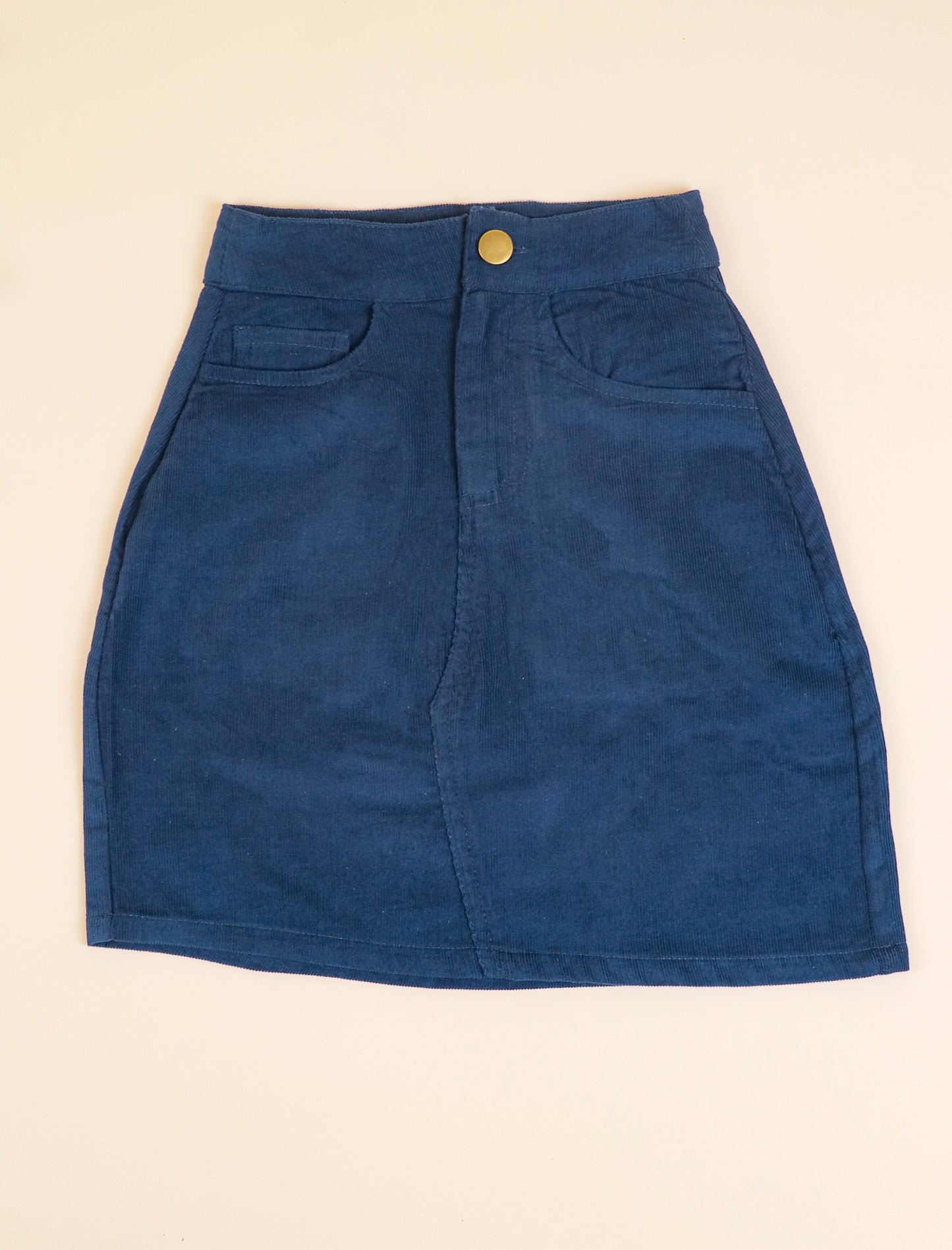 Blue skirt with a gold button on a beige background