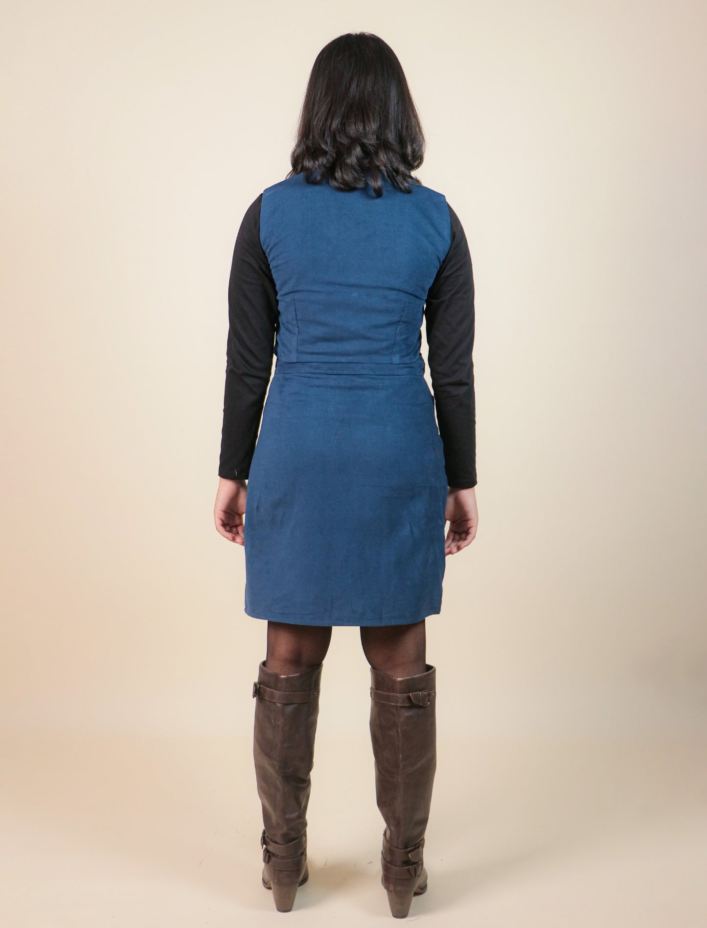 Girls wearing a blue dress with a black long-sleeve top and brown knee-high boots on a beige background