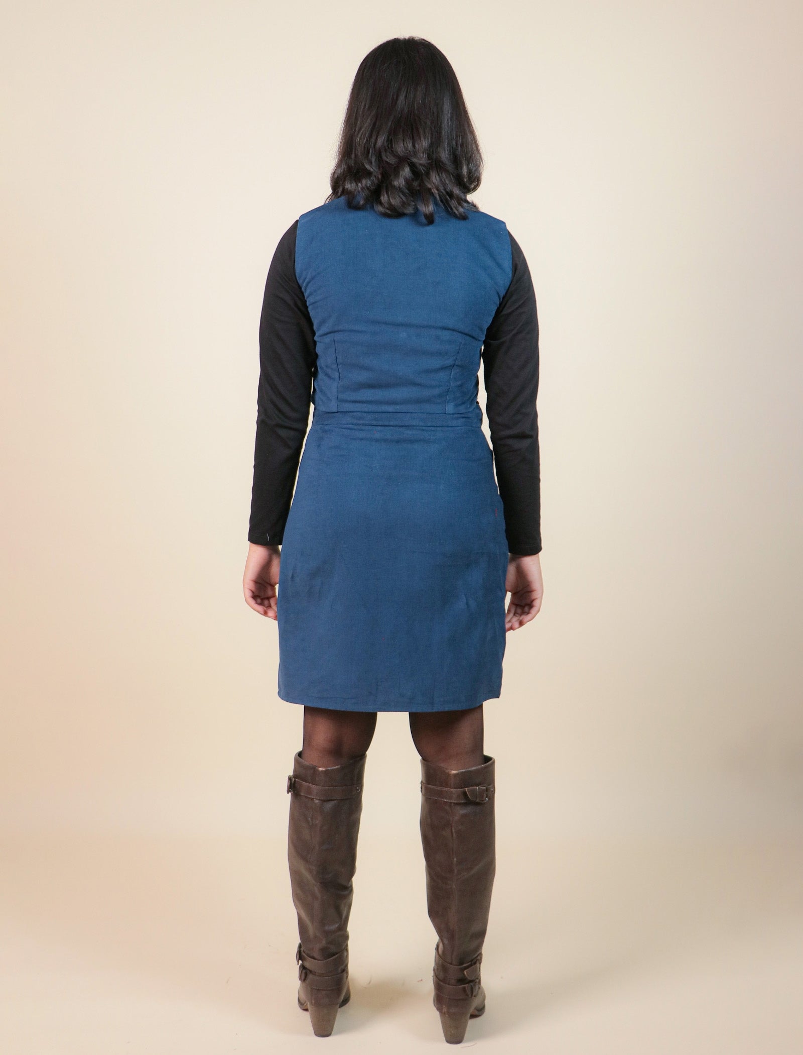 Girls wearing a blue dress with a black long-sleeve top and brown knee-high boots on a beige background