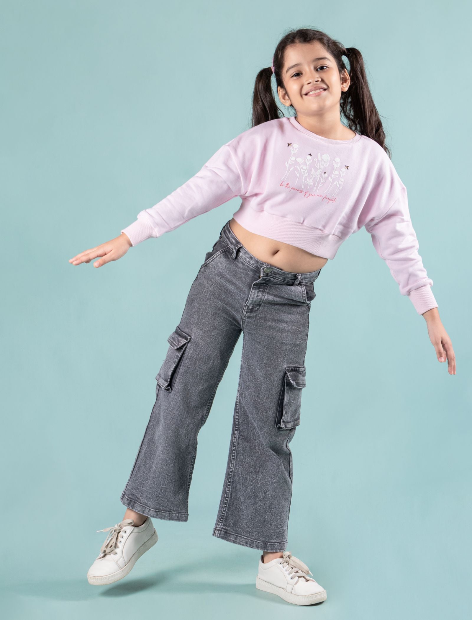 Girls wearing a winter sweatshirt pink colour and gray cargo pants on a light blue background