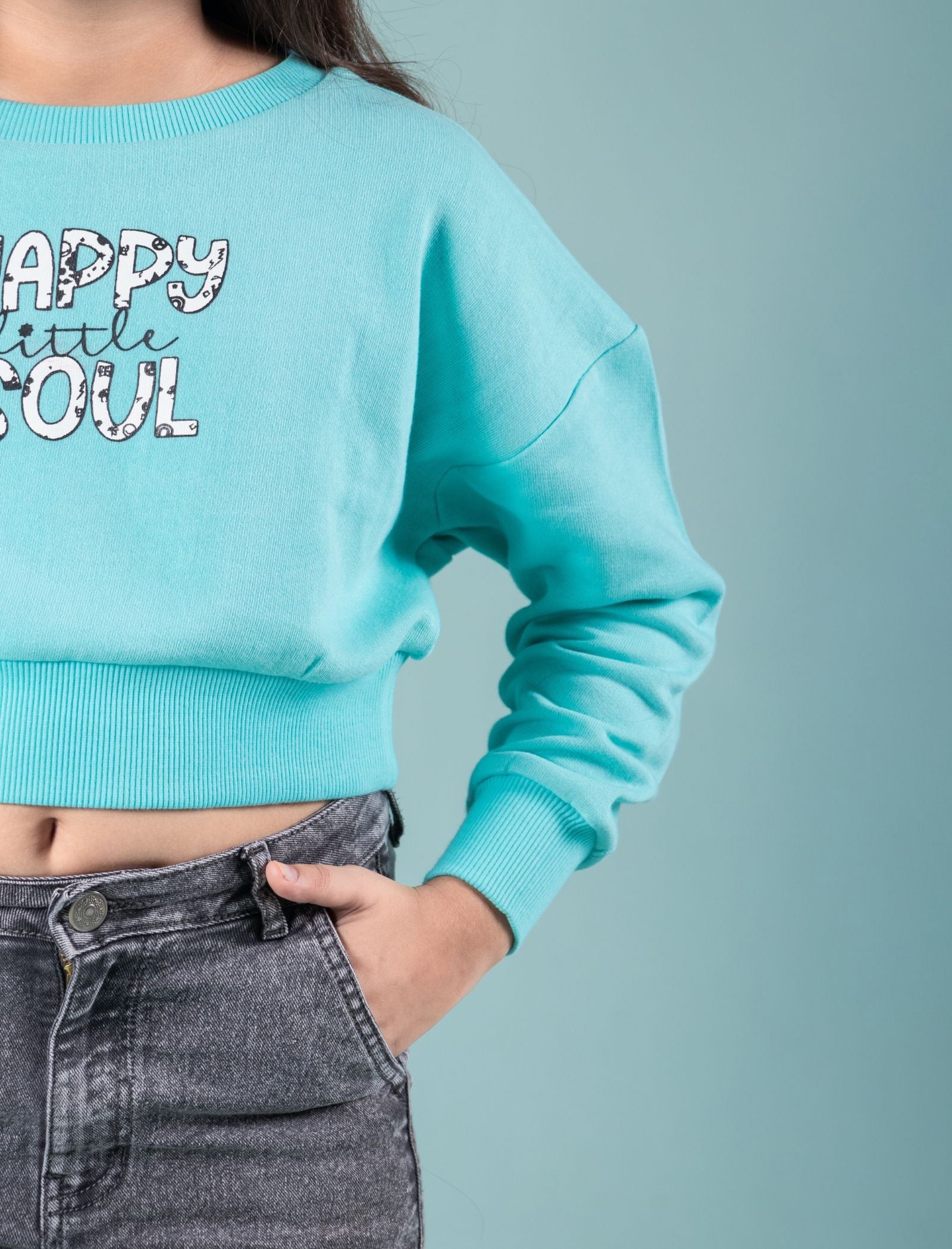 Kids wearing a light blue winter sweatshirt with text and gray pants on a plain background