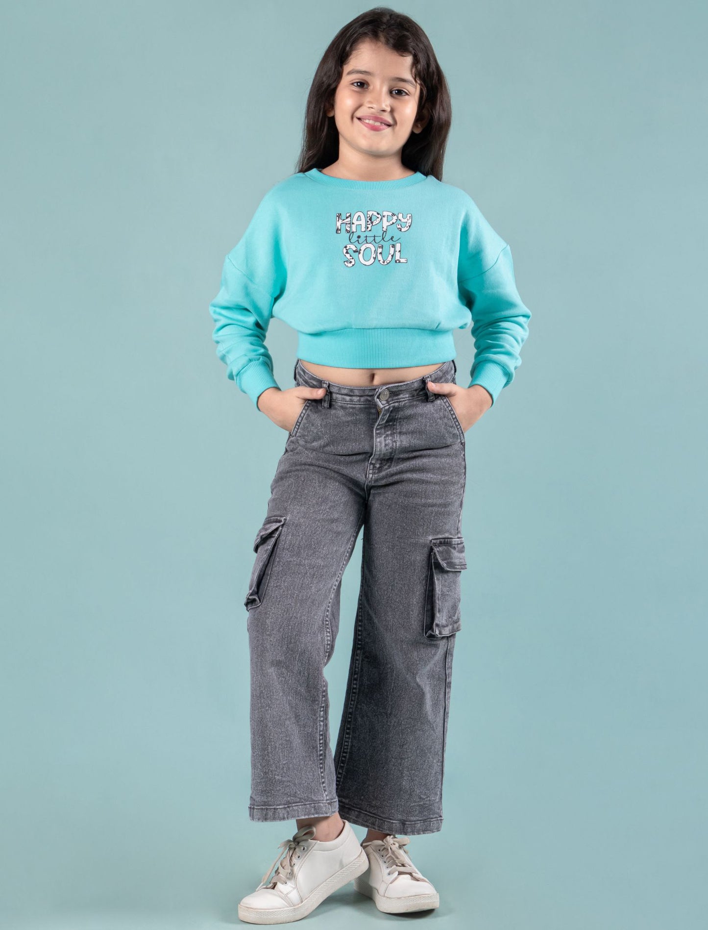 Kids wearing a turquoise winter sweatshirt and gray cargo pants on a light blue background