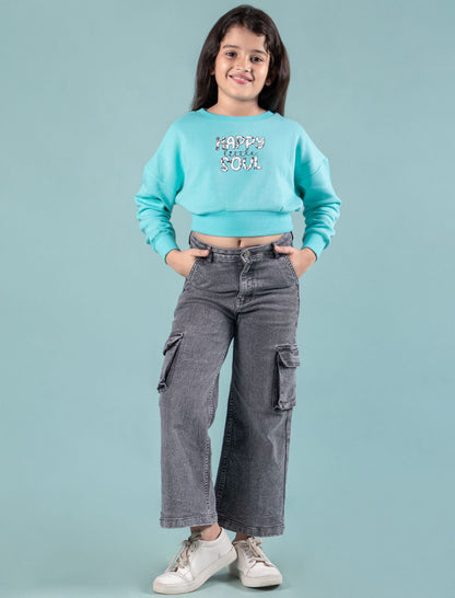 Kids wearing a turquoise winter sweatshirt and gray cargo pants on a light blue background