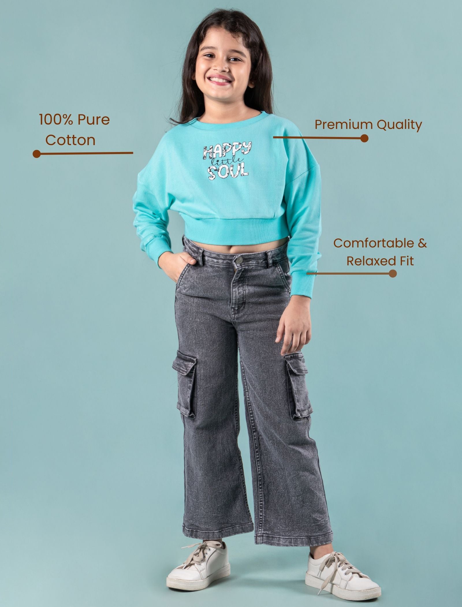 Girls kids wearing a turquoise winter sweatshirt and gray cargo pants on a light blue background