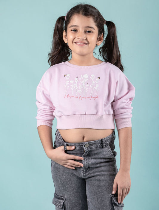Girls wearing a pink cropped winter sweatshirt with text and graphics on a light blue background