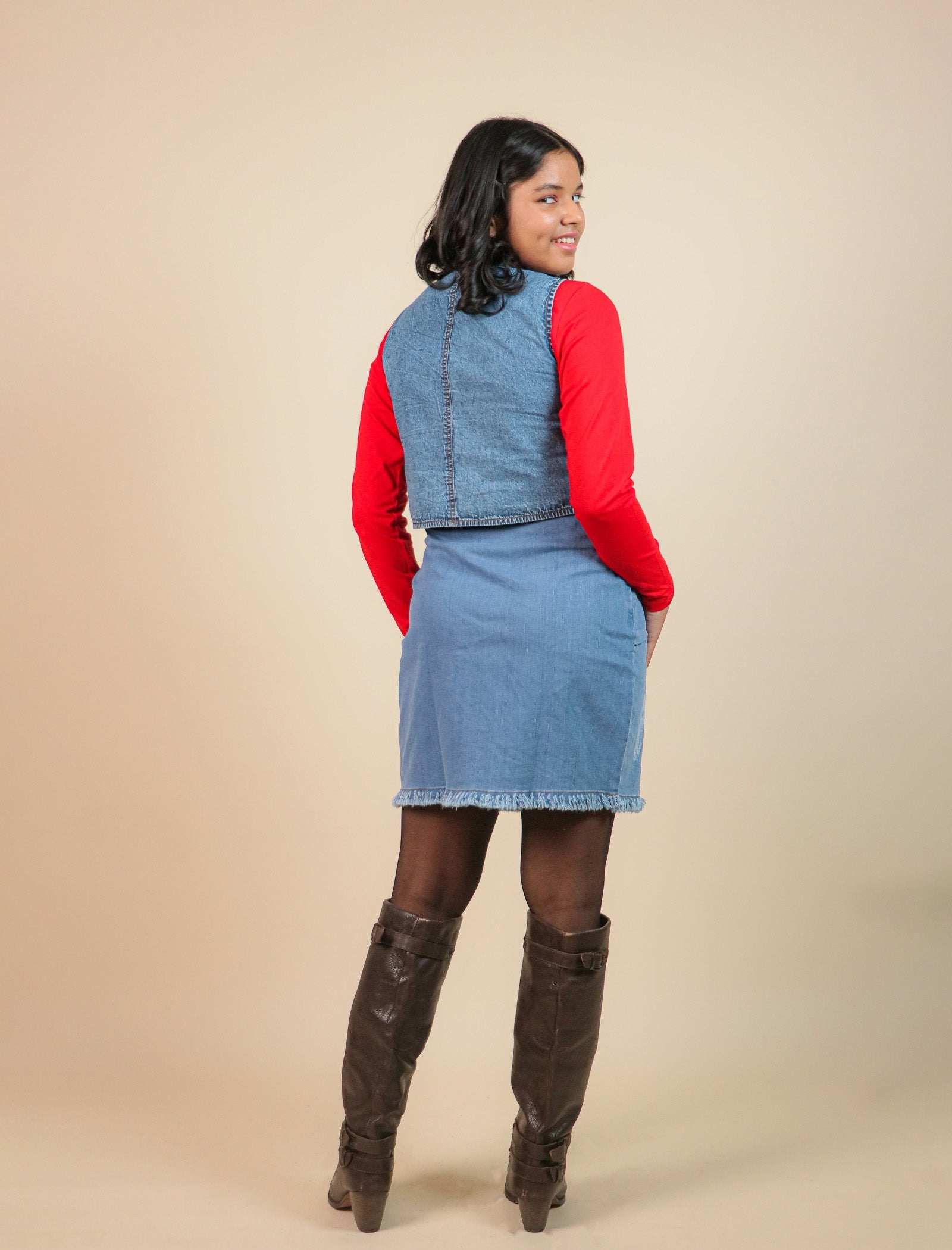 Girls wearing a denim outfit with a red sweater and brown knee-high boots on a beige background