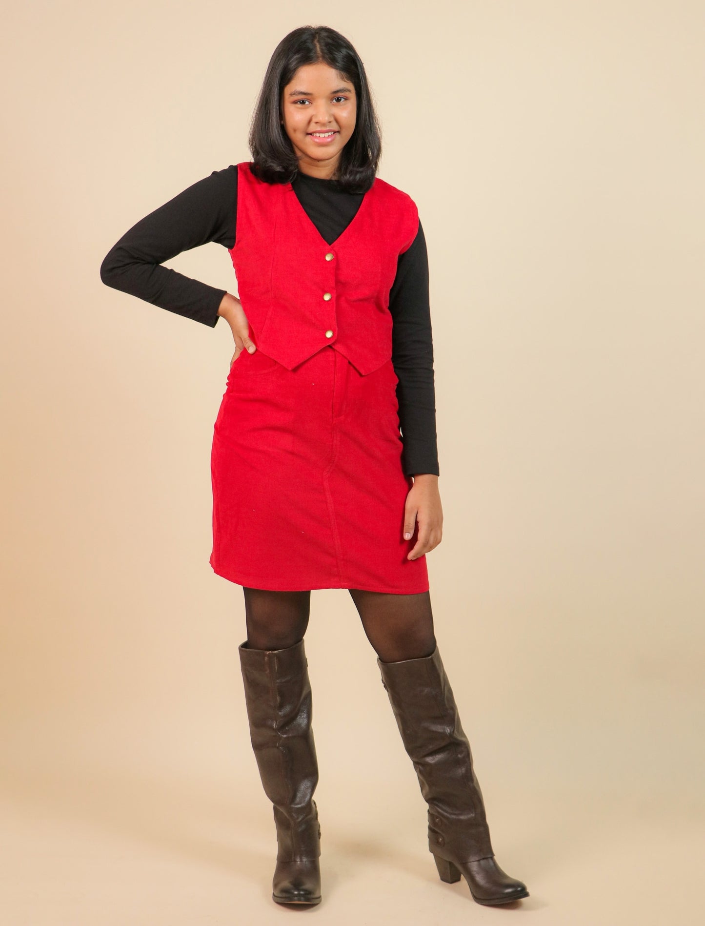 Girls wearing a red dress with a black top and brown boots on a beige background