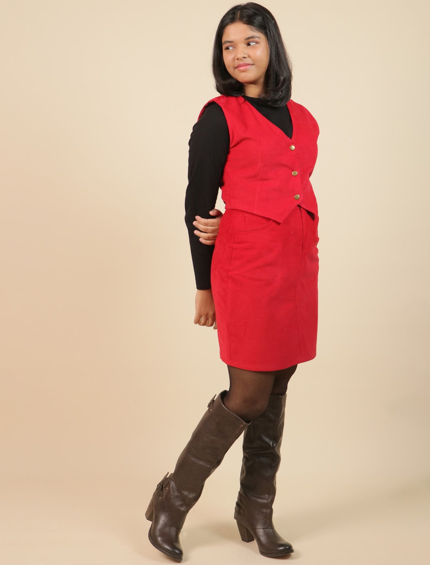 Girls wearing a red dress with a black top and brown boots on a beige background