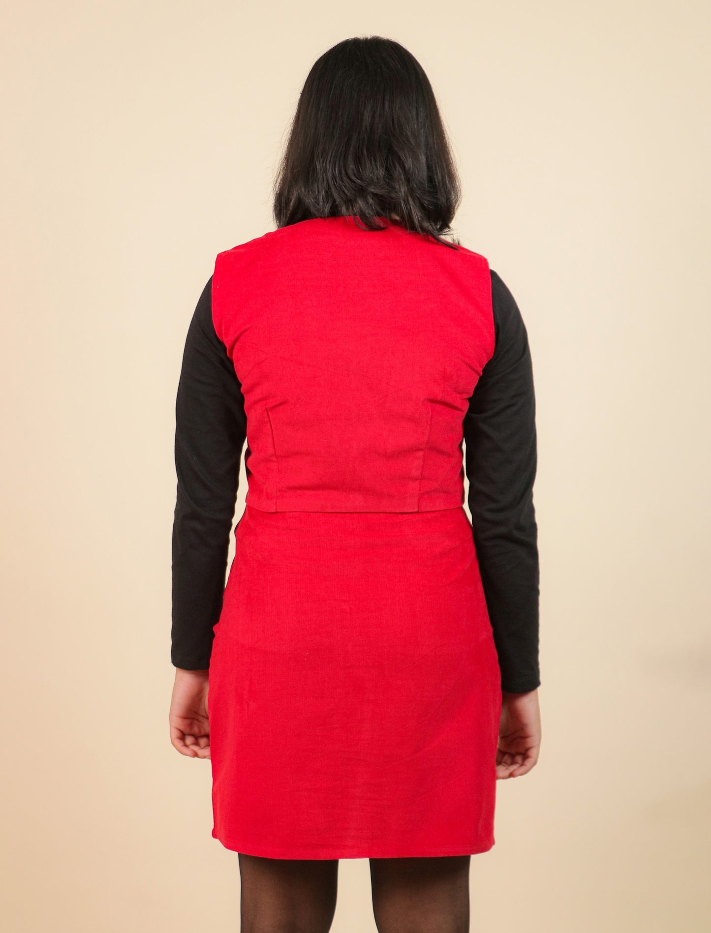 Girls wearing a red puffer vest over a black long-sleeve shirt on a beige background
