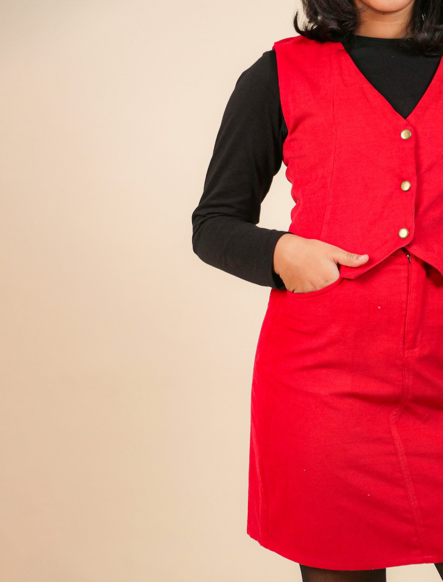 Girls wearing a red dress with a black long-sleeve shirt underneath on a beige background