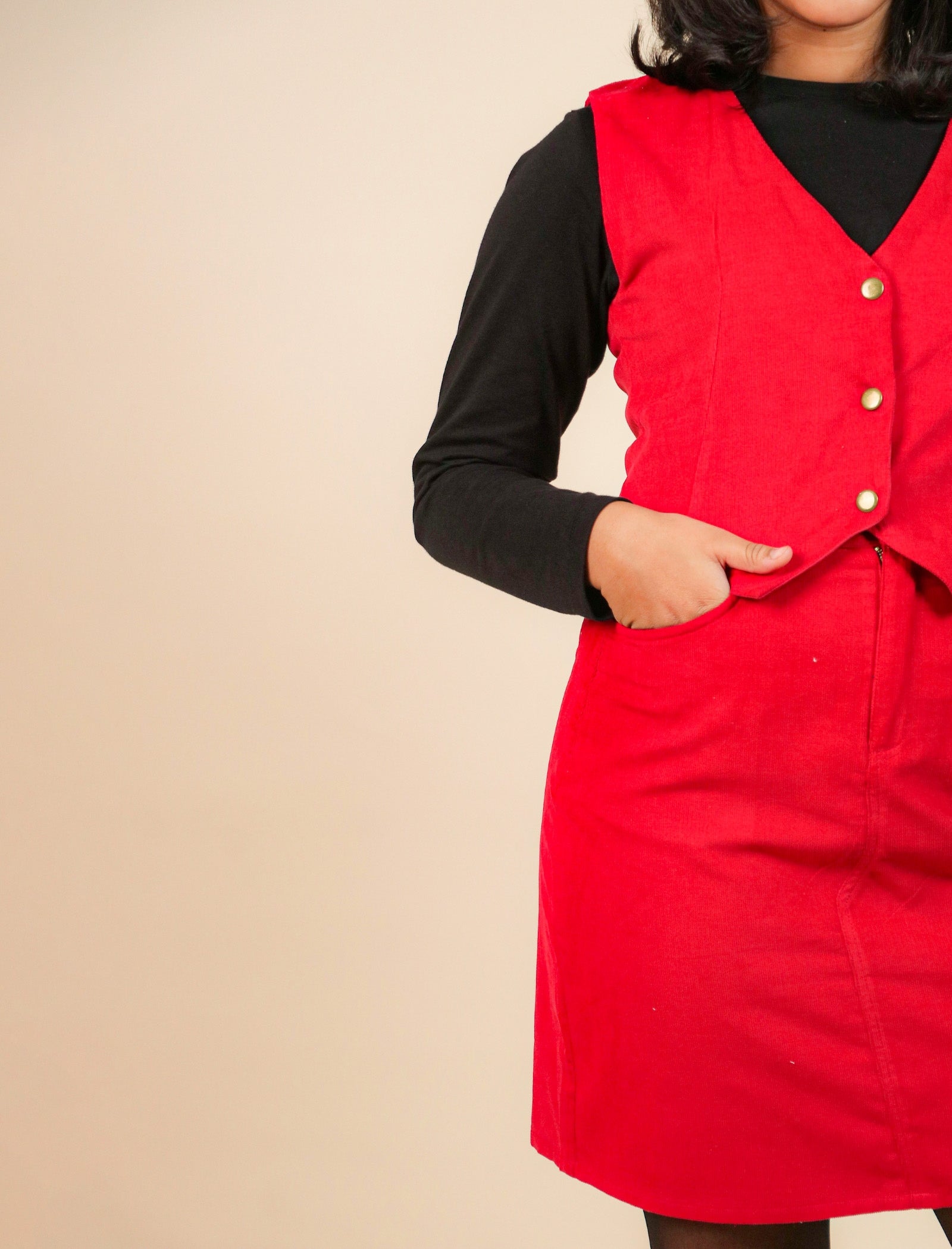 Girls wearing a red dress with a black long-sleeve shirt underneath on a beige background